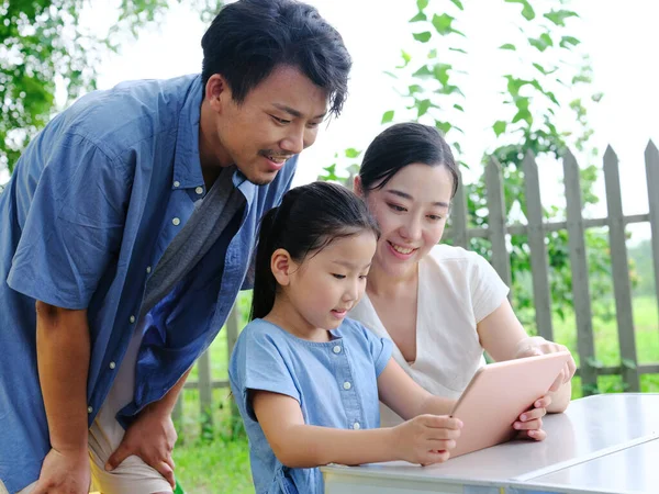 Família feliz de três usos tablet computador ao ar livre — Fotografia de Stock