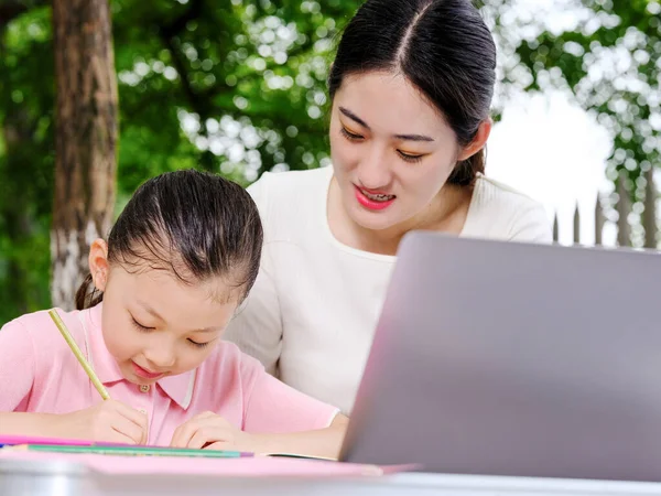 Unga mödrar hjälper sina barn med läxorna — Stockfoto