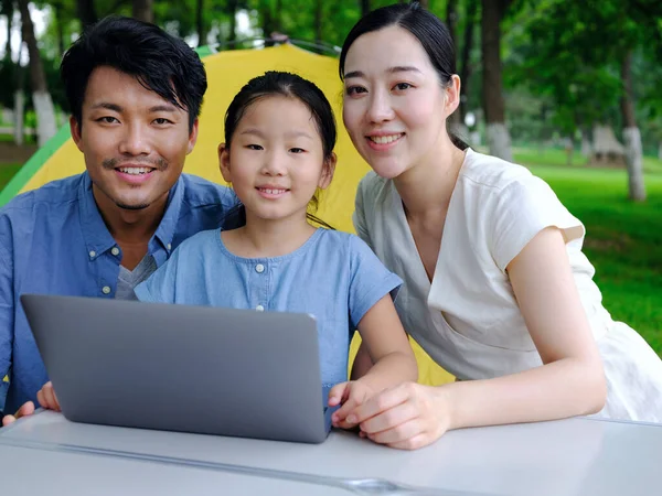 Happy family of three use computer to surf the Internet outdoors — Stock Photo, Image