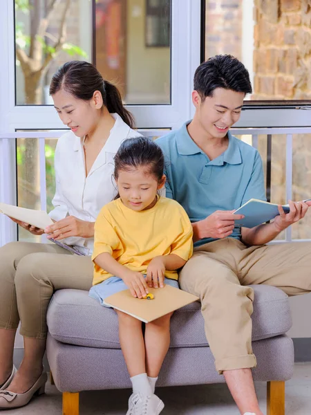 Eine glückliche dreiköpfige Familie liest auf dem Sofa — Stockfoto
