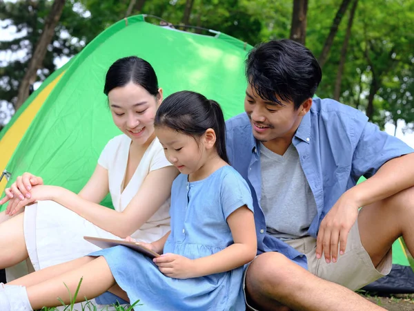 Happy family of three uses tablet computer outdoors — Stock Photo, Image