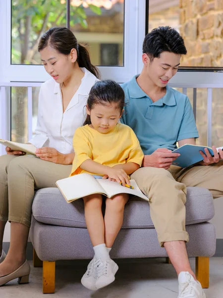 A happy family of three reading on the sofa — Stock Photo, Image