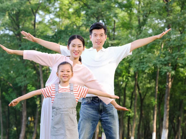 Família feliz de três brincando no parque — Fotografia de Stock