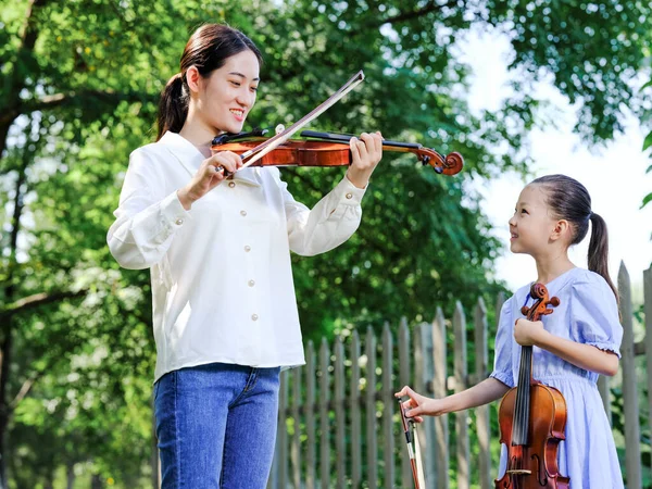 A professora instrui a menina a tocar violino no parque ao ar livre — Fotografia de Stock