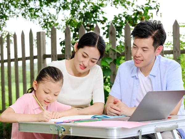 Junge Eltern helfen ihren Kindern bei den Hausaufgaben im Freien — Stockfoto