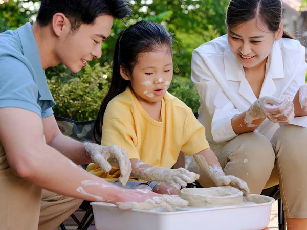 Happy family of three doing pottery together outdoors — Stock Photo, Image