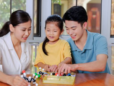 Üç kişilik mutlu bir aile moleküler yapı modelini birlikte yapıyor.