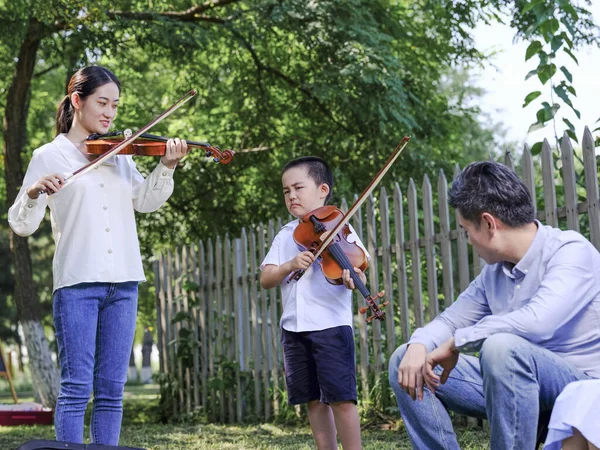 Famiglia felice di tre che suonano il violino nel parco — Foto Stock