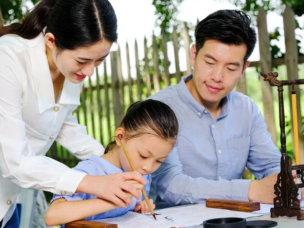 Glückliche dreiköpfige Familie schreibt Kalligraphie im Freien — Stockfoto