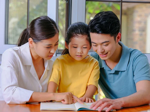 Eine glückliche dreiköpfige Familie liest zusammen — Stockfoto