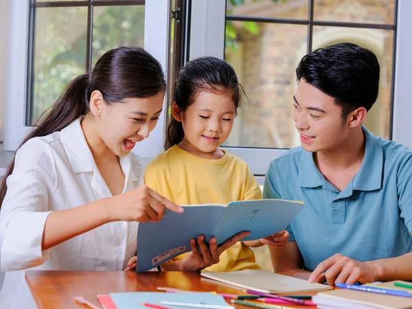Junge Eltern helfen ihren Kindern bei den Hausaufgaben — Stockfoto
