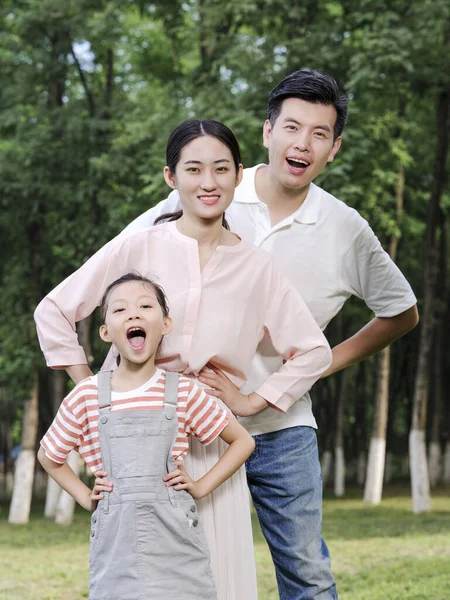 Família feliz de três brincando no parque — Fotografia de Stock