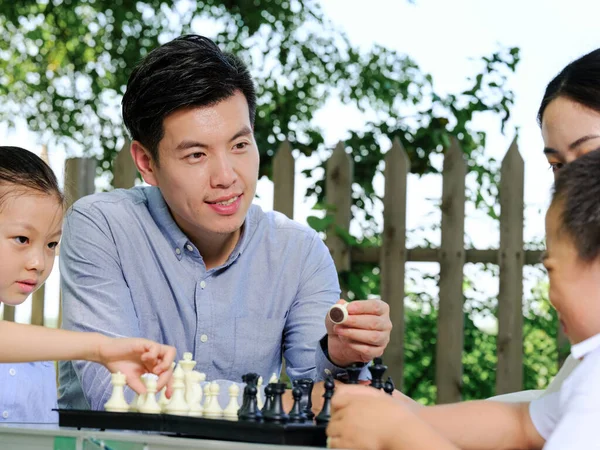 Счастливая семья из четырех человек играет в шахматы в парке — стоковое фото