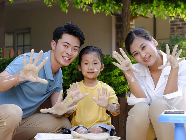 Happy family of three doing pottery together outdoors — Stock Photo, Image