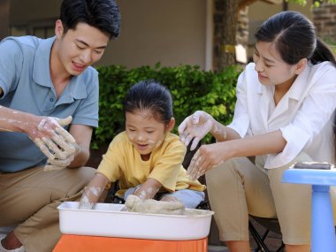 Üç kişilik mutlu aile dışarıda çömlekçilik yapıyor.