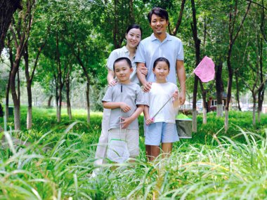 Dışarıda böcek yakalayan dört kişilik mutlu bir aile.