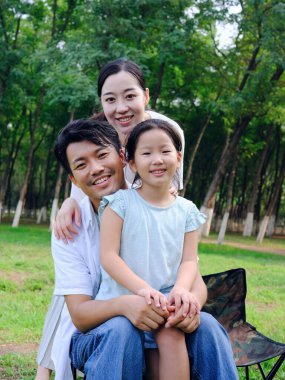 Üç kişilik mutlu bir aile parkta oynuyor.