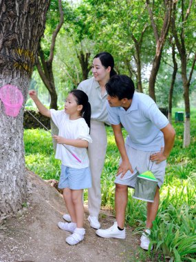 Üç kişilik mutlu bir aile dışarıda böcek yakalar.