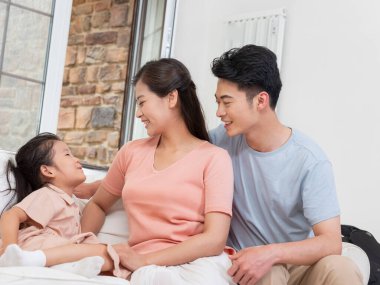 Üç kişilik mutlu bir aile oturma odasındaki kanepede oturuyor.