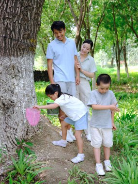 Dışarıda böcek yakalayan dört kişilik mutlu bir aile.