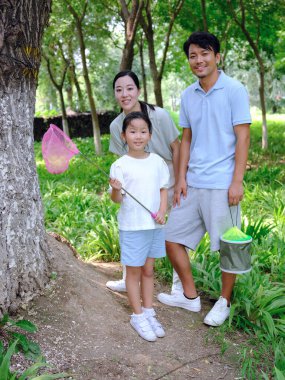 Üç kişilik mutlu bir aile dışarıda böcek yakalar.