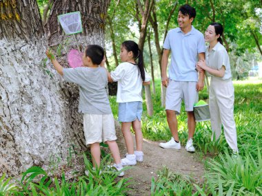 Dışarıda böcek yakalayan dört kişilik mutlu bir aile.