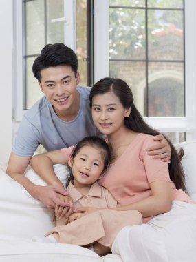 Üç kişilik mutlu bir aile oturma odasındaki kanepede oturuyor.