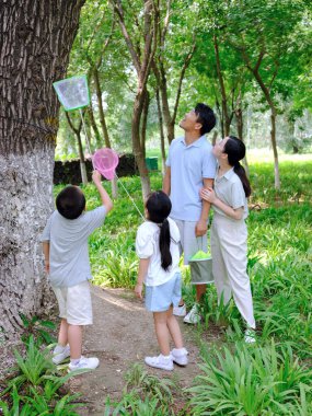 Dışarıda böcek yakalayan dört kişilik mutlu bir aile.