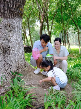 Üç kişilik mutlu bir aile dışarıda böcek yakalar.