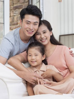 Üç kişilik mutlu bir aile oturma odasındaki kanepede oturuyor.