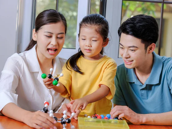 Glückliche dreiköpfige Familie macht gemeinsam Molekularstrukturmodell — Stockfoto