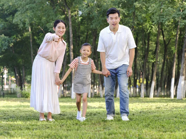 Família feliz de três brincando no parque — Fotografia de Stock