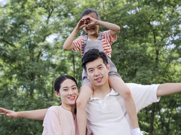 Família feliz de três brincando no parque — Fotografia de Stock