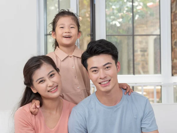 Una familia feliz de tres está sentada en el sofá de la sala de estar —  Fotos de Stock