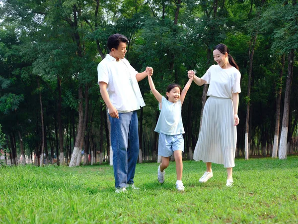 Família feliz de três brincando no parque — Fotografia de Stock