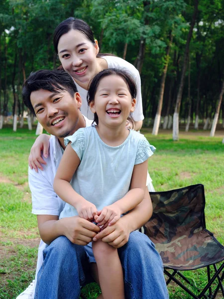 Família feliz de três brincando no parque — Fotografia de Stock