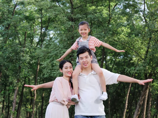 Família feliz de três brincando no parque — Fotografia de Stock