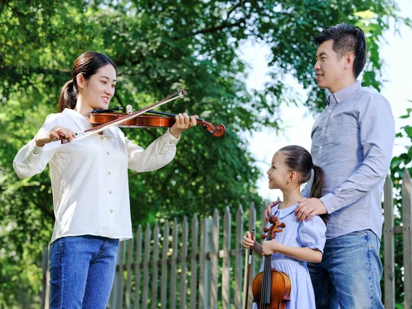 Lycklig familj på tre som spelar fiol i parken — Stockfoto