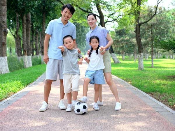 Счастливая семья из четырех человек играет в футбол в парке — стоковое фото