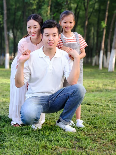 Família feliz de três brincando no parque — Fotografia de Stock