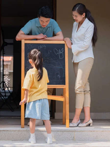 Eine glückliche dreiköpfige Familie malt draußen — Stockfoto