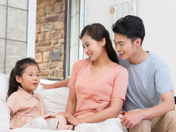 A happy family of three is sitting on the sofa in the living room — Stock Photo, Image