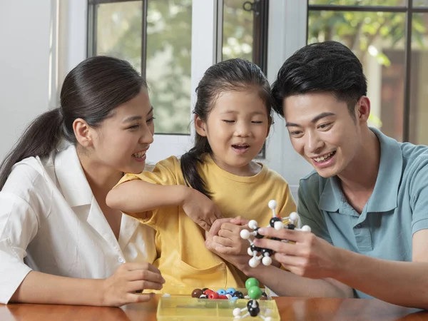 Glückliche dreiköpfige Familie macht gemeinsam Molekularstrukturmodell — Stockfoto