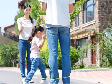 Dışarıda ip atlayan mutlu bir aile.