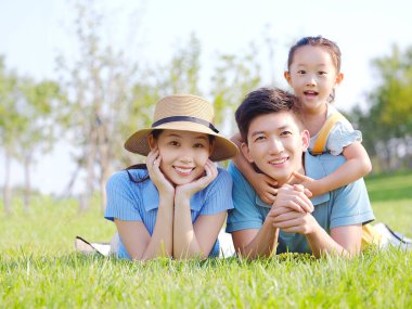 Üç kişilik mutlu bir aile çimlerin üzerinde