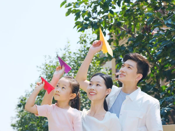 Šťastná rodina tří vrhacích papírových letadel venku — Stock fotografie