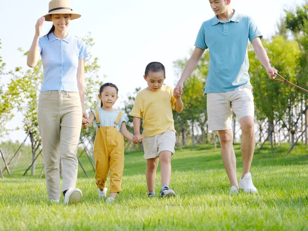 Una familia feliz de cuatro caminando por el parque —  Fotos de Stock