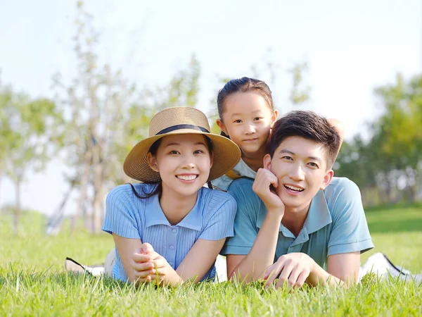 Família feliz de três na grama — Fotografia de Stock