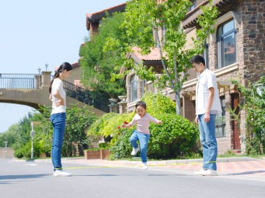 Dışarıda ip atlayan mutlu bir aile.