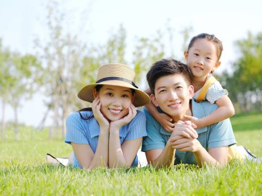 Üç kişilik mutlu bir aile çimlerin üzerinde